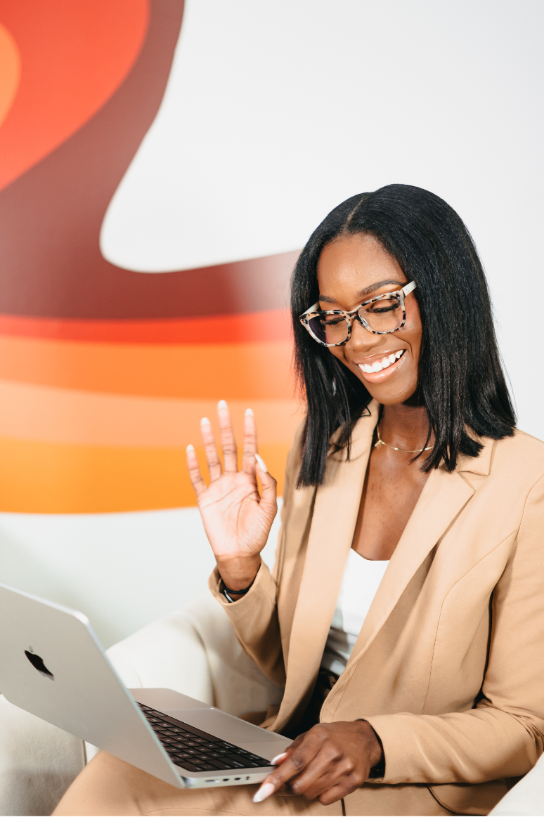 Woman in a beige suit using a laptop with a colorful abstract design in the background